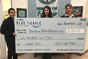 Ms. Holmes holding oversize check with Principal Steele and bank representative