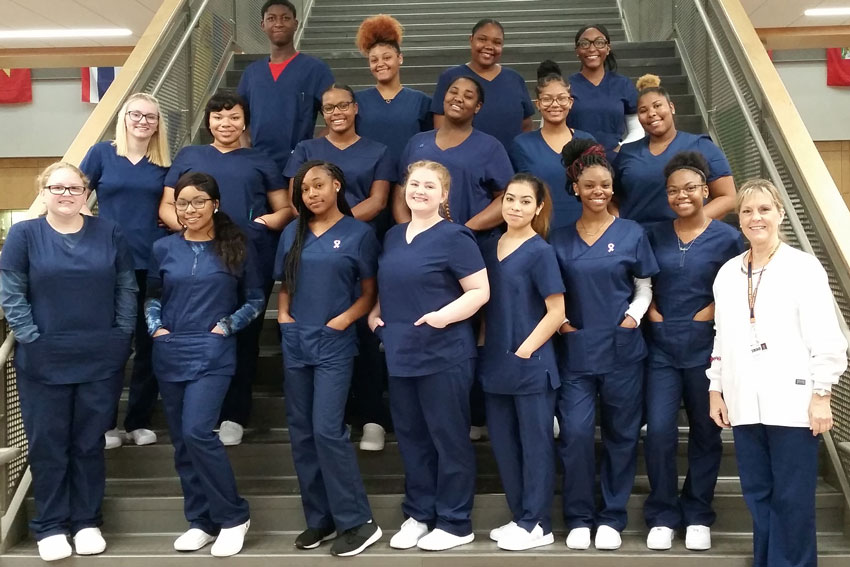 Nurse aide students wearing scrubs standing on steps