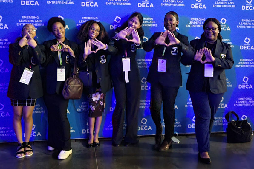 Students in front of DECA Emerging Leaders and Entrepreneurs backdrop