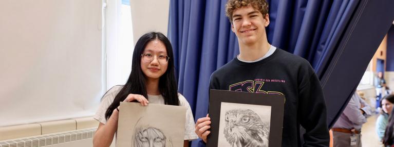 Two students holding artwork