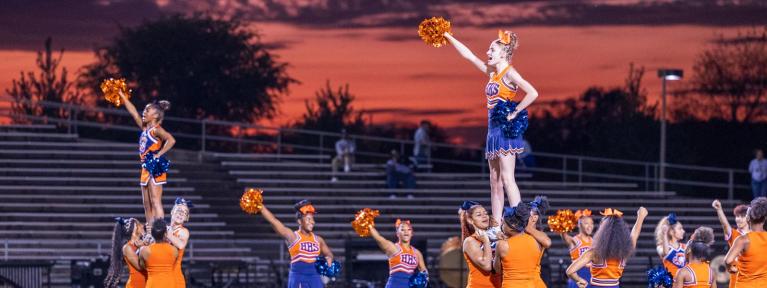 Cheerleaders on field with orange sky