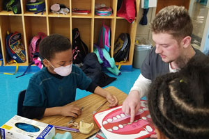 Dental Careers student points to chart while talking to elementary kids