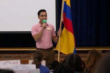 Man holding flag of Columbia in front of student assembly