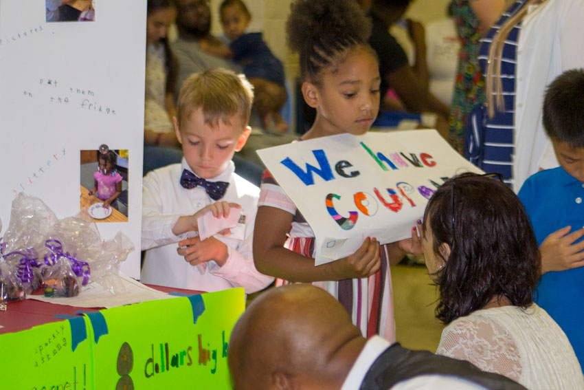 Elementary student with sign standing in front of display