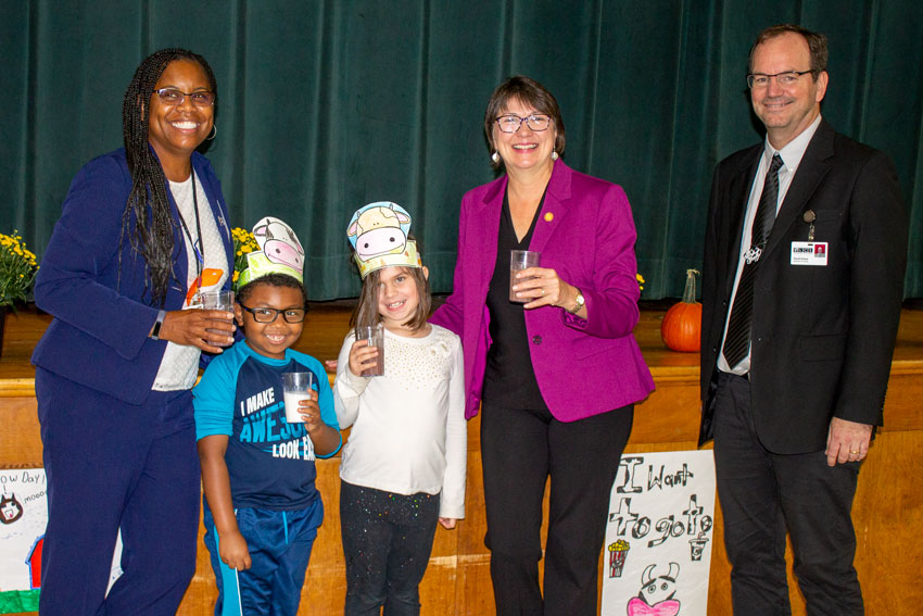Administrators and students pose with Virginia Secretary of Agriculture Betina Ring while holding glasses of milk