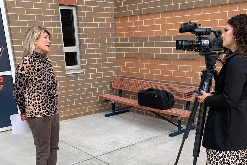 Director of School Nutrition standing outside school being interviewed by reporter