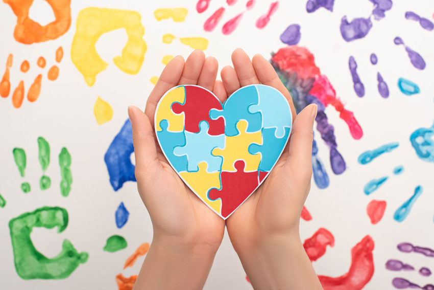 Hands holding heart with puzzle shapes