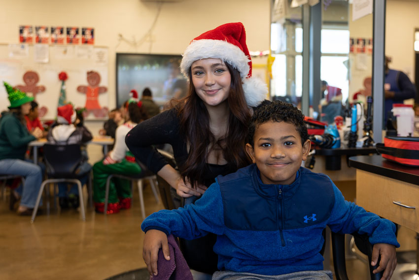 Elementary student in salon chair with cosmetology student