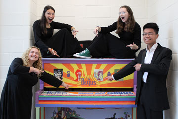 String quartet pointing at piano painted with Beatles logo