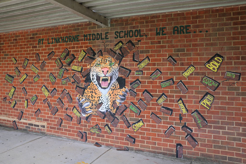 Mural of jaguar busting through bricks that read at Linkhorne Middle School We Are...