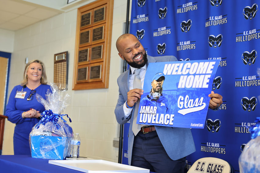 Coach Jamar Lovelace holding welcome sign at press conference