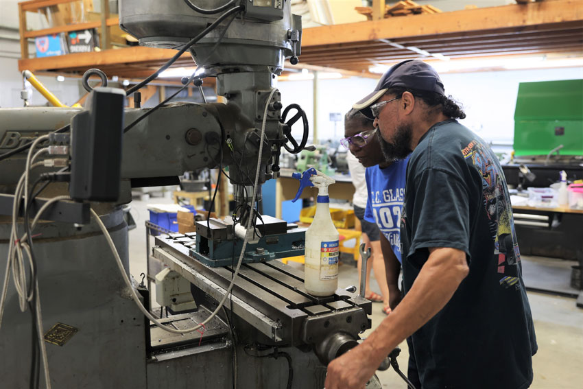 Woman with instructor operating machining equipment