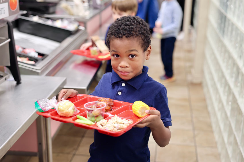 Student in cafeteria line with lunch tray