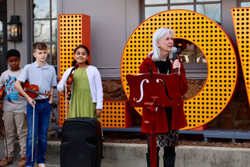 Teacher speaking with strings students in background