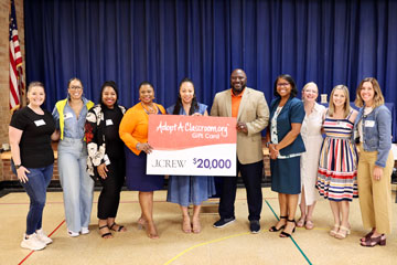 J.Crew representative with LCS administrators and staff holding donation sign