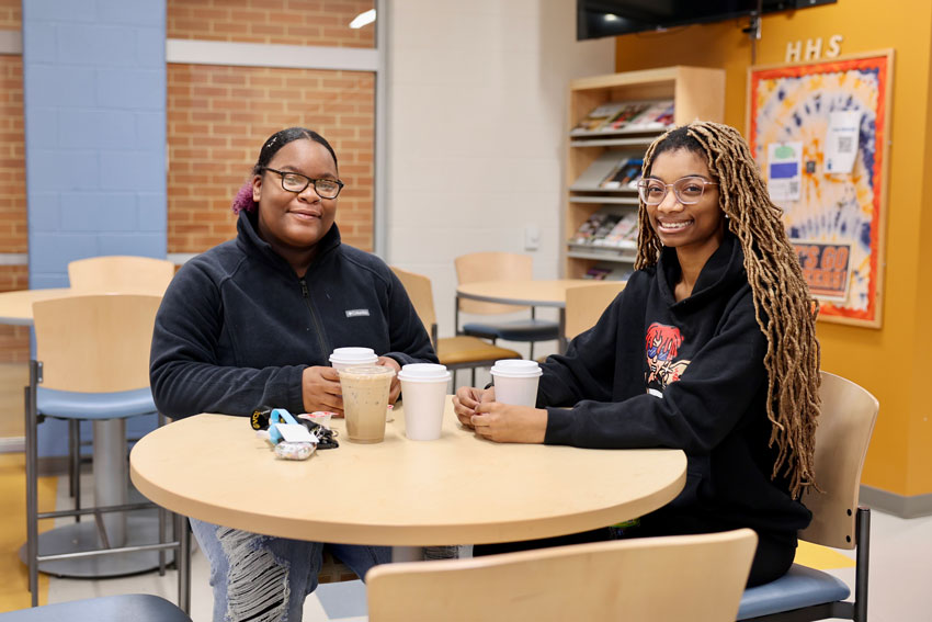 Two students at table with cups of coffee