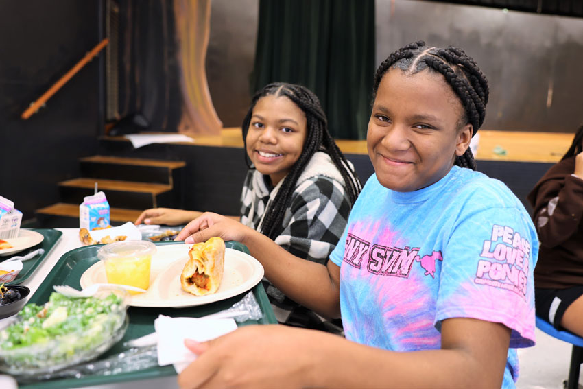 Two middle school students at lunch table smiling