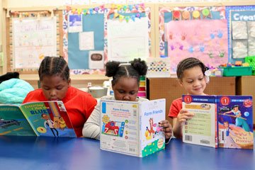 Three elementary students reading at a table