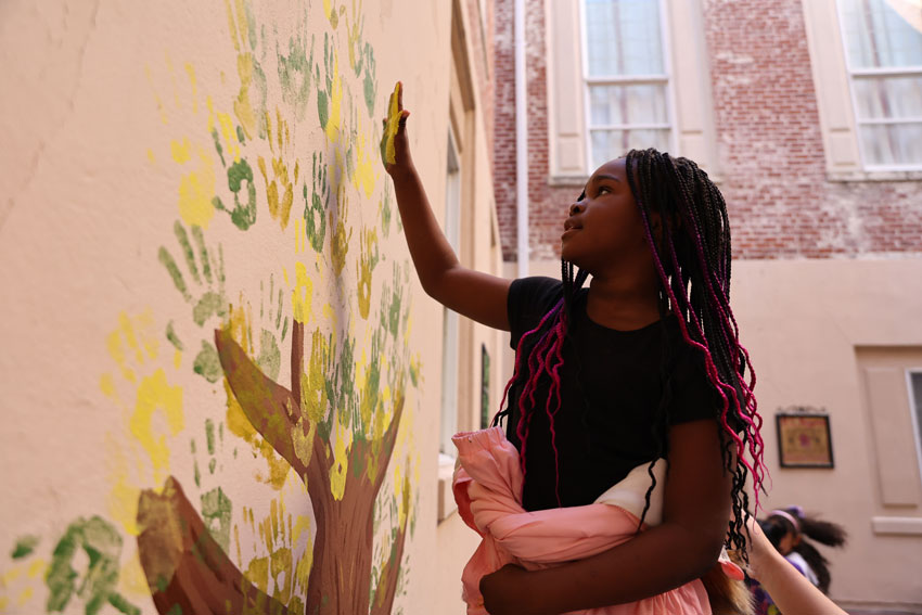 Student painting mural on wall