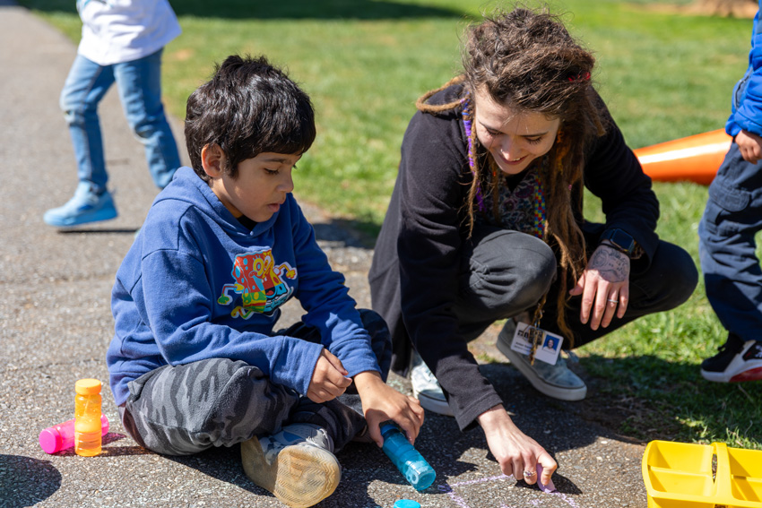 Behavior coach with student using sidewalk chalk