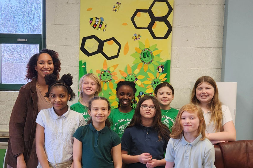 Students with artist standing in front of mural project
