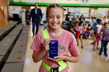 Student in safety patrol belt holding AAA award