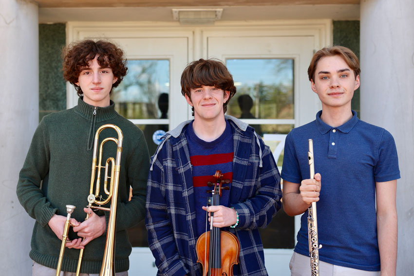 Three students holding musical instruments
