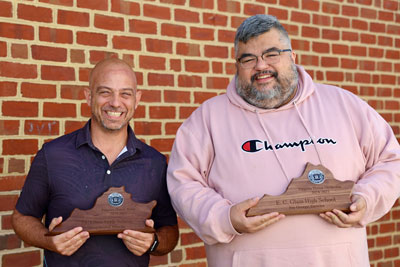 Two teachers holding awards