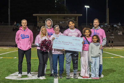 Students and staff in pink shirts presenting donation check