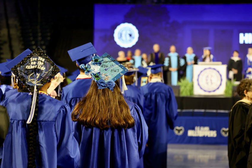 Graduates in caps and gowns standing at commencement ceremony