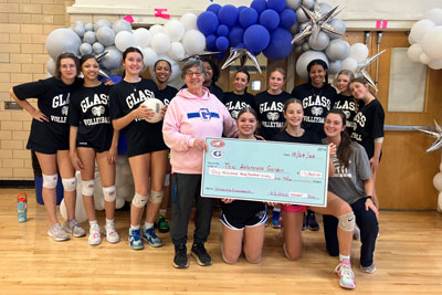 Volleyball team with school volunteer holding donation check