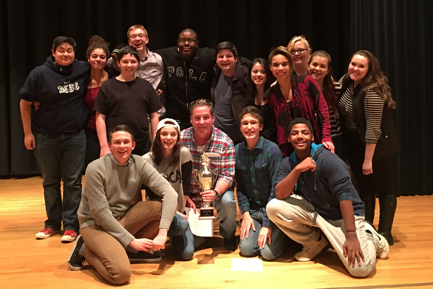 Teacher with students holding theatre competition trophy