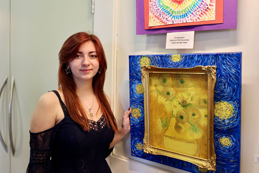 Student standing in front of artwork being displayed