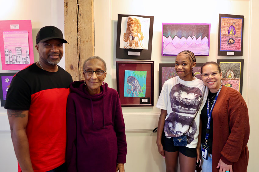 Student with her family standing in front of artwork being displayed