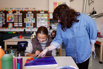 Art teacher Tory Duffy giving painting instructions to student Annie Richards