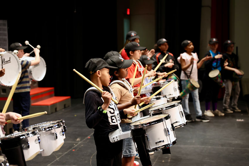 Elementary students playing drums on stage
