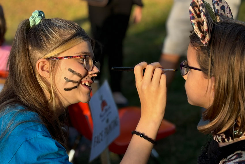 Student painting a face at community event