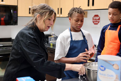 Teacher demonstrating culinary arts techniques to two students