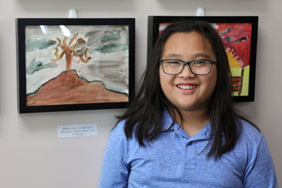 Student standing in front of artwork on display