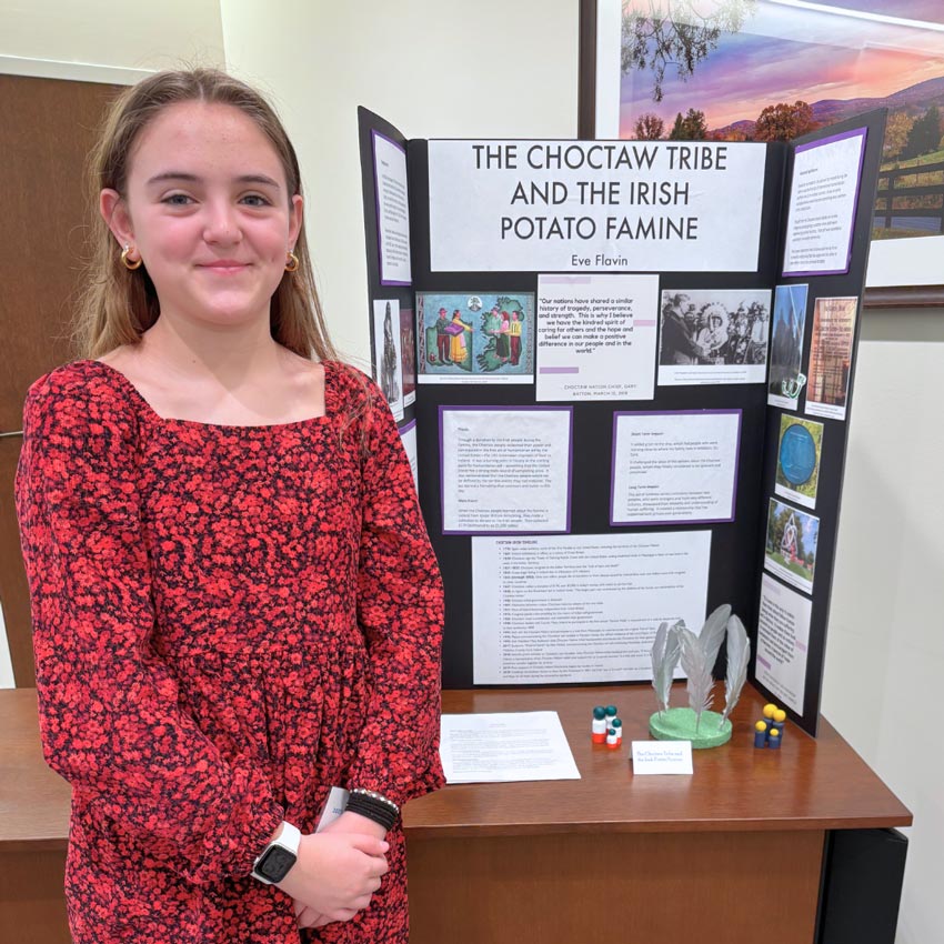 Eve Flavin standing in front of “The Choctaw Tribe and the Irish Potato Famine” project display