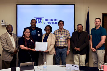 School Board members with Superintendent Dr. Kristy Somerville-Midgette holding plaque in School Board Room