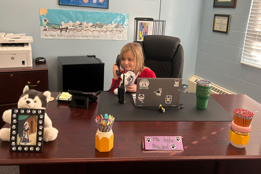 Elementary student at desk talking on telephone