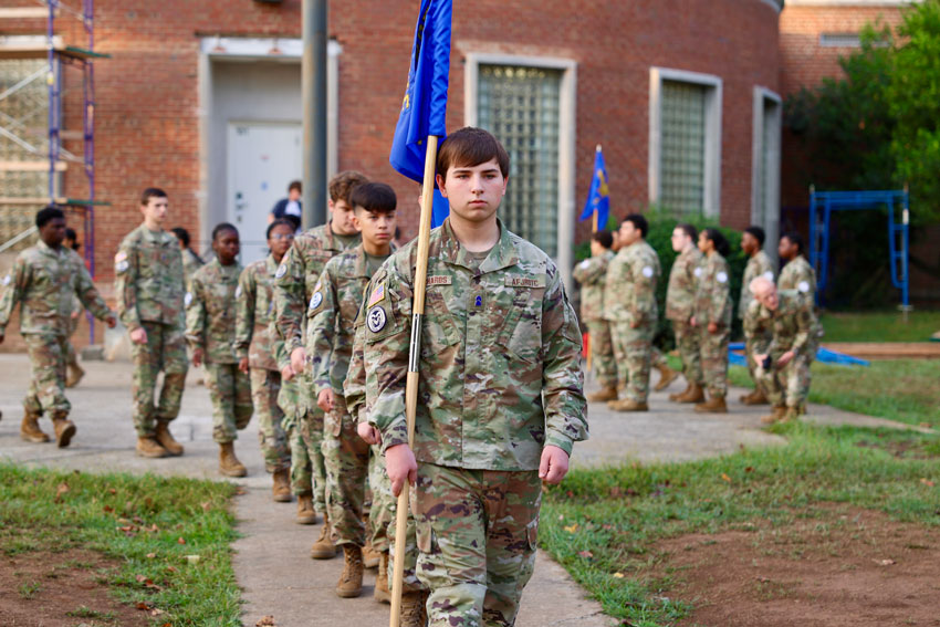 JROTC cadets marching from flag pole outside school