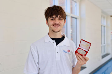 Ezra Mancier holding SkillsUSA award in school hallway