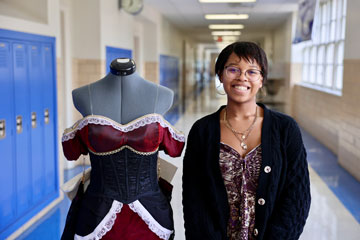 Student standing in school hallway with dress on mannequin