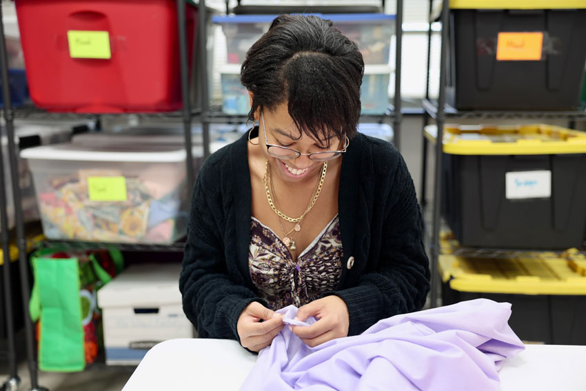Student smiling while working with fabric
