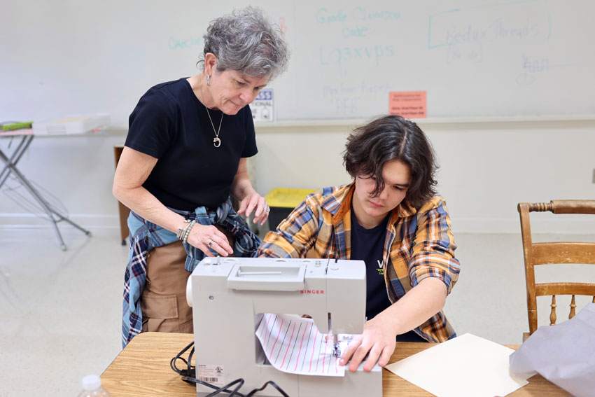 Teacher with student working with sewing machine