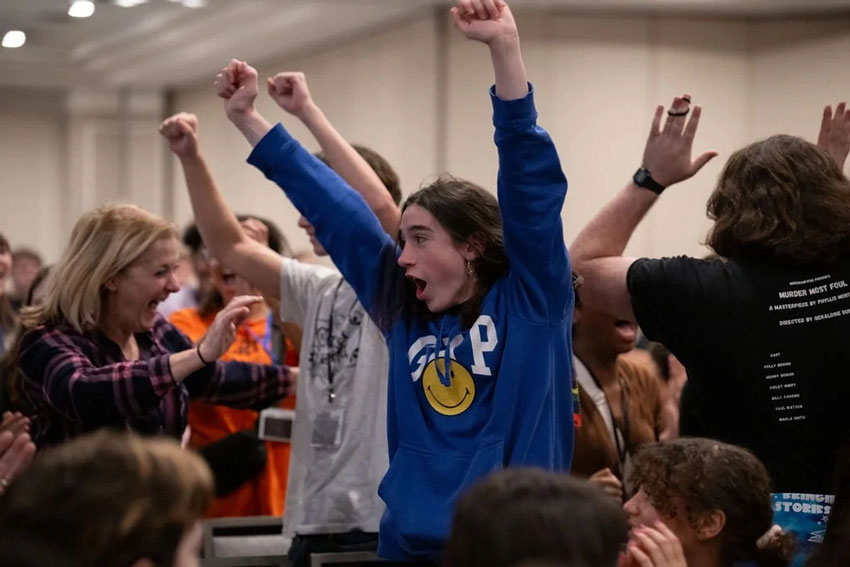 Theatre students and teacher jumping up in celebration