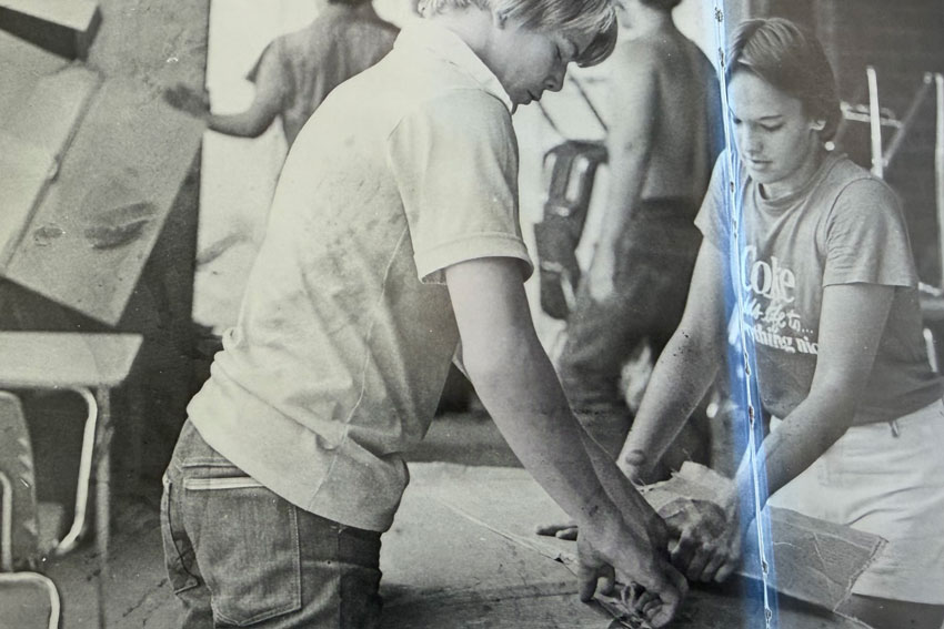 Black and white photo of two students unpacking a box