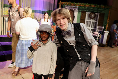 High school drama student in costume with elementary student